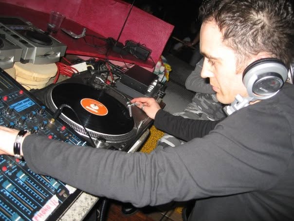 Le mani di DJ Millo su un giradischi con un vinile.